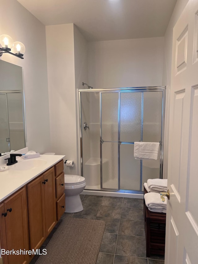 bathroom with tile patterned flooring, vanity, toilet, and a shower with shower door