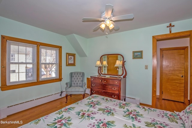 bedroom with a baseboard radiator, baseboard heating, wood finished floors, and a ceiling fan