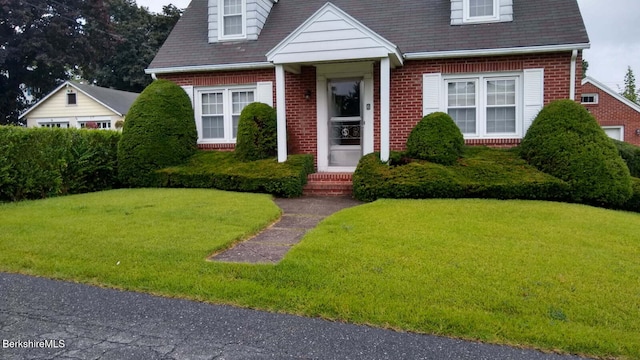 cape cod house with a front yard and brick siding