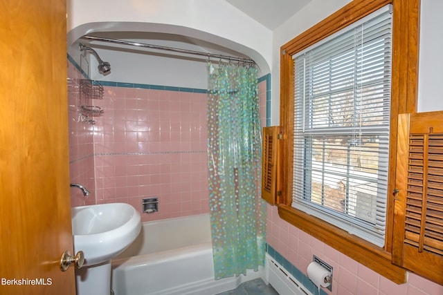 bathroom featuring tile walls, shower / bathtub combination with curtain, and a sink