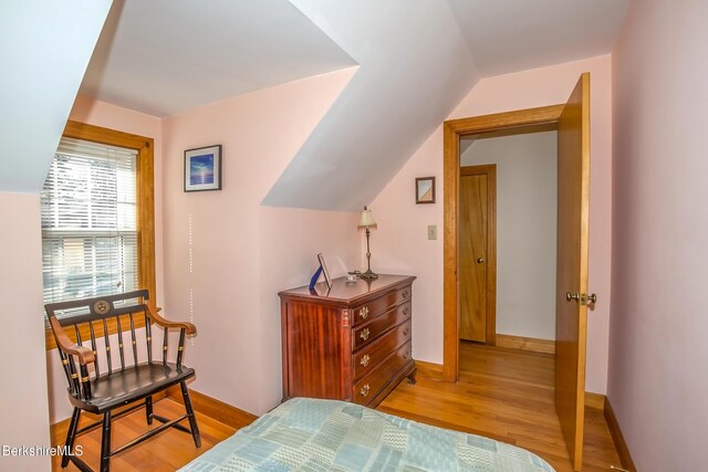 bedroom with baseboards, light wood-style flooring, and vaulted ceiling