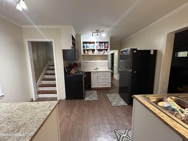 kitchen with backsplash, hardwood / wood-style flooring, ornamental molding, and black appliances