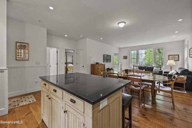 kitchen featuring wood-type flooring, open floor plan, a kitchen island, wainscoting, and recessed lighting