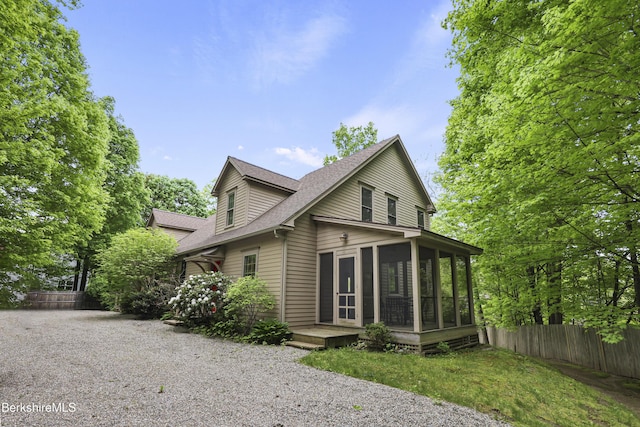 view of property exterior with a sunroom, fence, and roof with shingles