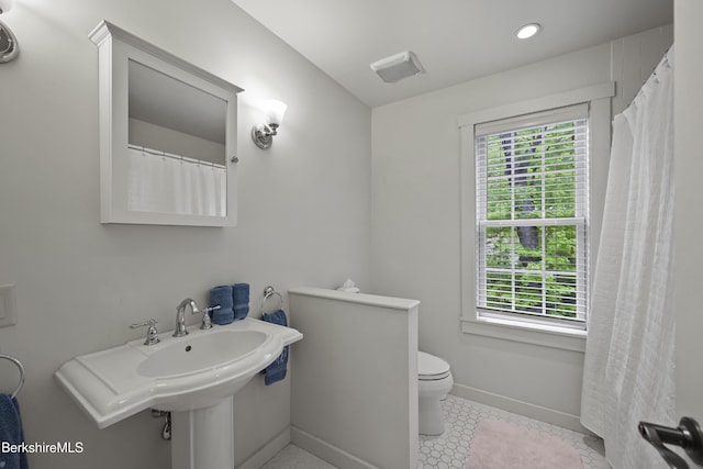 bathroom with plenty of natural light, baseboards, toilet, tile patterned floors, and recessed lighting