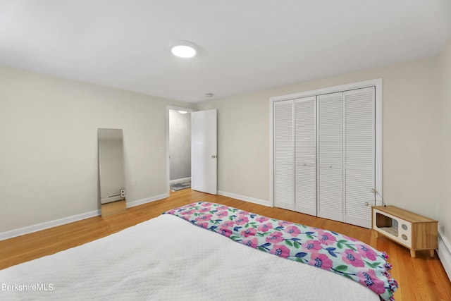 bedroom with baseboard heating, a closet, and wood-type flooring