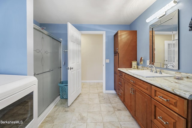 bathroom with vanity, a shower with shower door, and washer / dryer