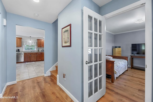 corridor with sink, ornamental molding, and light hardwood / wood-style flooring