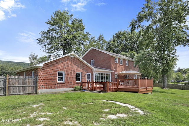 rear view of house featuring a lawn and a deck