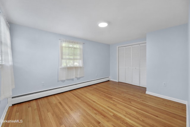 unfurnished bedroom with light hardwood / wood-style floors, a closet, and a baseboard radiator