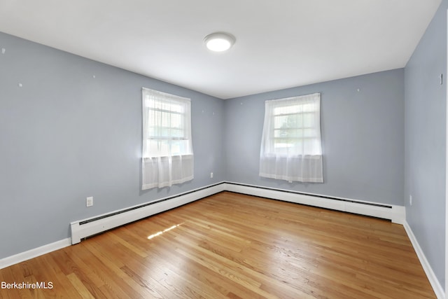 unfurnished room featuring a baseboard radiator and light hardwood / wood-style floors