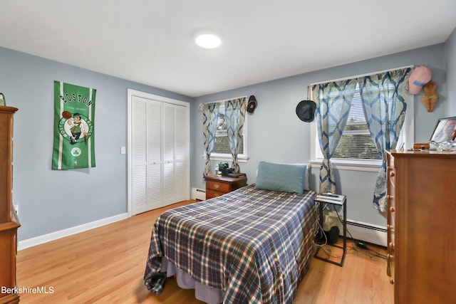 bedroom featuring hardwood / wood-style floors, a closet, and a baseboard heating unit