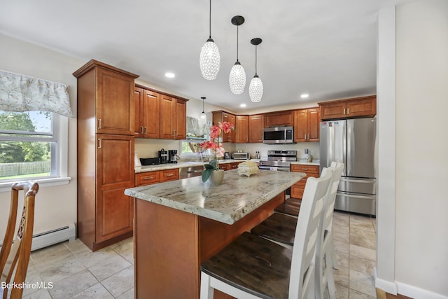 kitchen with light stone countertops, a center island, hanging light fixtures, a breakfast bar area, and appliances with stainless steel finishes