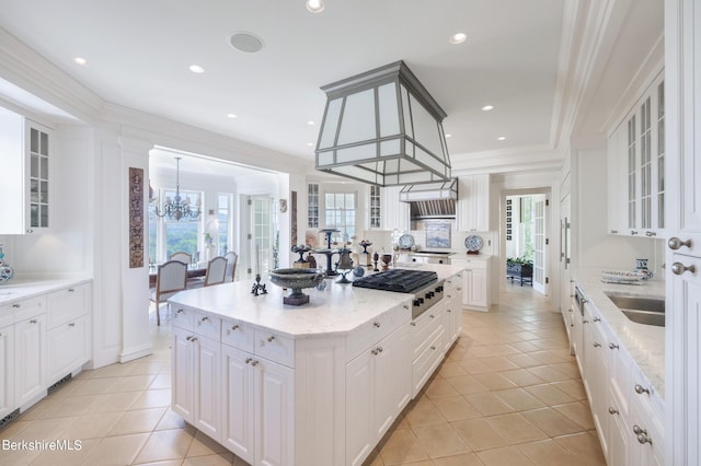 kitchen featuring decorative light fixtures, a kitchen island, stainless steel gas cooktop, and white cabinetry