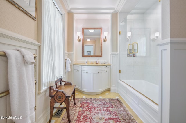 bathroom featuring vanity, bath / shower combo with glass door, and ornamental molding