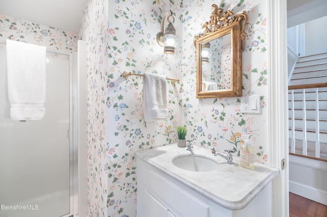 bathroom with hardwood / wood-style floors, vanity, and a shower with door