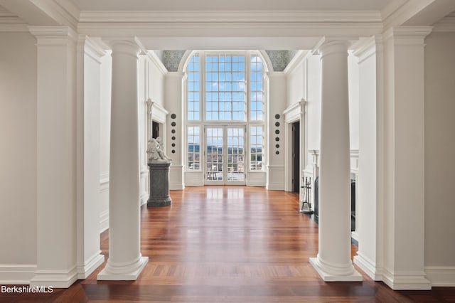 entryway featuring decorative columns, wood-type flooring, ornamental molding, and french doors