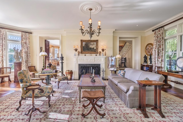 living room with a wealth of natural light, crown molding, a premium fireplace, and an inviting chandelier