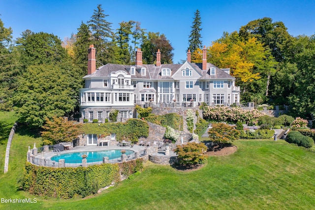 rear view of property with a lawn and a fenced in pool