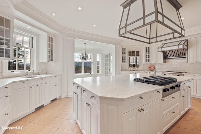 kitchen with a center island, an inviting chandelier, hanging light fixtures, decorative backsplash, and stainless steel gas cooktop