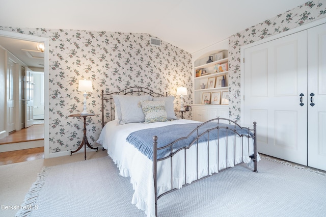 carpeted bedroom with vaulted ceiling and a closet