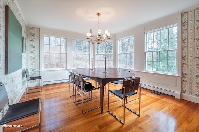 dining space featuring an inviting chandelier, a baseboard heating unit, and light hardwood / wood-style flooring