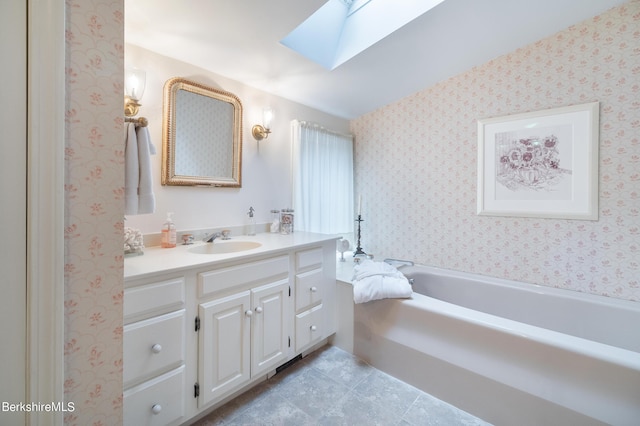 bathroom featuring a skylight, a bathtub, and vanity