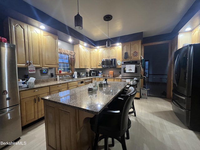 kitchen featuring stainless steel appliances, sink, pendant lighting, a center island, and a breakfast bar area