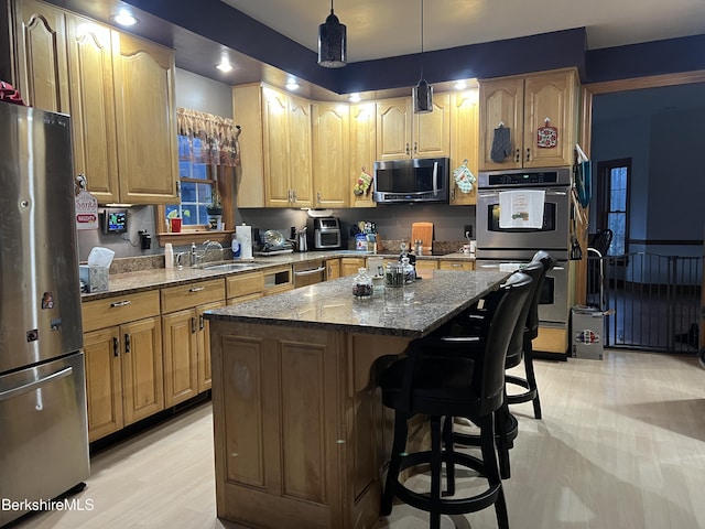 kitchen featuring stone counters, appliances with stainless steel finishes, decorative light fixtures, and a kitchen island