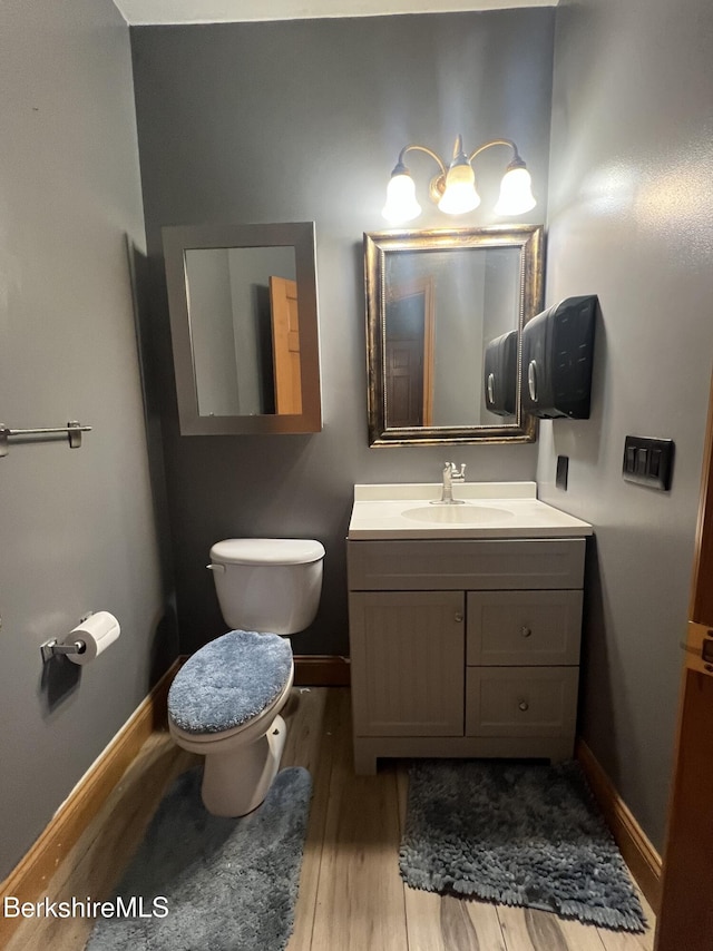 bathroom with hardwood / wood-style flooring, vanity, and toilet