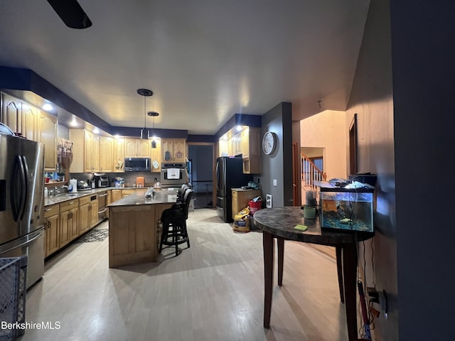 kitchen featuring sink, stainless steel appliances, pendant lighting, a kitchen bar, and a kitchen island