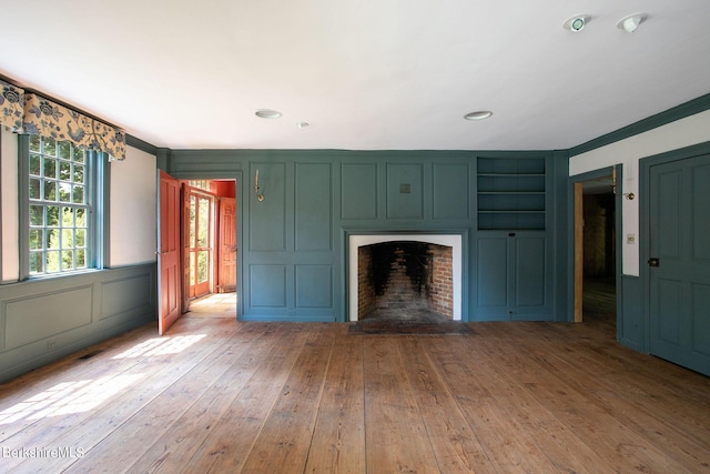 unfurnished living room with crown molding, wood-type flooring, and a brick fireplace