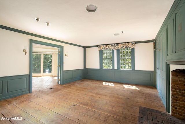 unfurnished room featuring a healthy amount of sunlight, light wood-type flooring, and crown molding