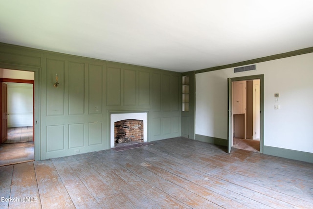 unfurnished living room featuring light wood-type flooring and ornamental molding