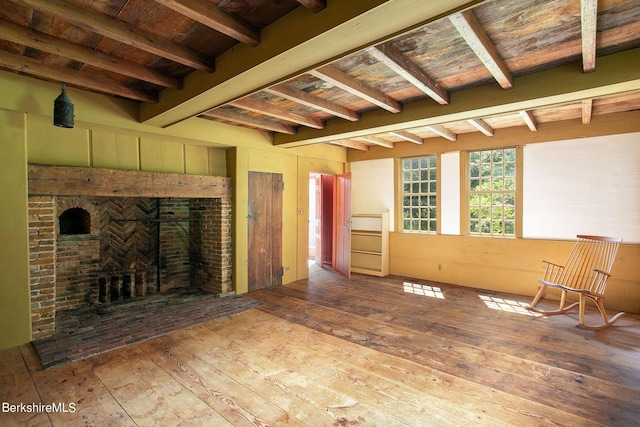 unfurnished living room with a fireplace, hardwood / wood-style floors, beamed ceiling, and wooden ceiling