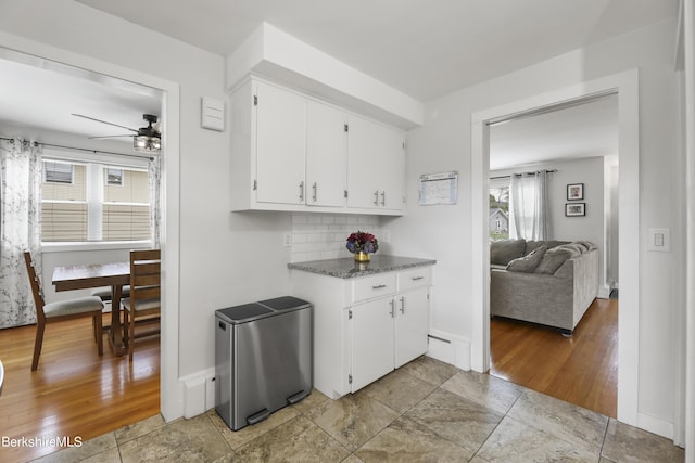 kitchen featuring backsplash, baseboards, light wood-style flooring, white cabinetry, and a ceiling fan