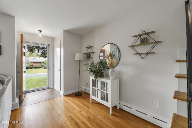 foyer entrance with light wood-type flooring, a baseboard radiator, and baseboards