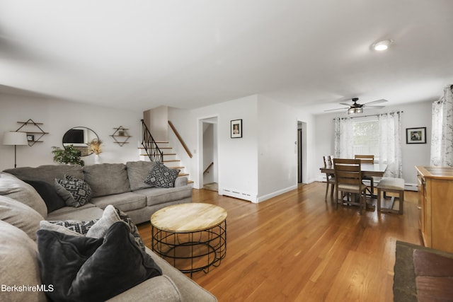 living area with stairway, wood finished floors, baseboards, and baseboard heating