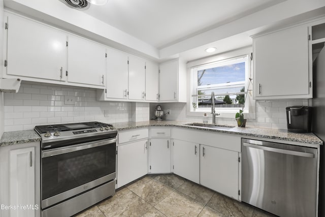 kitchen featuring a sink, light stone counters, backsplash, appliances with stainless steel finishes, and white cabinets