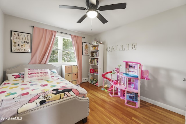 bedroom with a ceiling fan, wood finished floors, baseboards, and baseboard heating