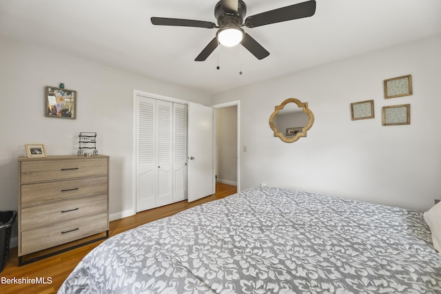 bedroom with a ceiling fan, wood finished floors, a closet, and baseboards