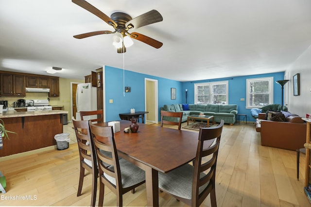 dining space with light wood finished floors, baseboards, and a ceiling fan