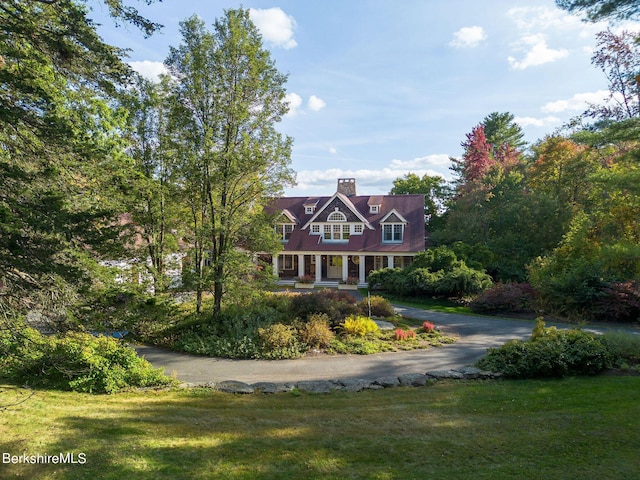 new england style home with covered porch and a front lawn