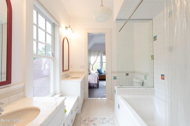 bathroom featuring a bathing tub, tile patterned floors, toilet, vanity, and tile walls