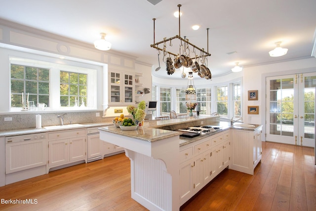 kitchen with sink, an island with sink, decorative light fixtures, white appliances, and white cabinets