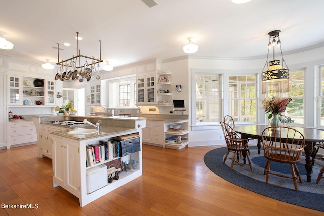 kitchen featuring a center island with sink, pendant lighting, white cabinets, and light wood-type flooring