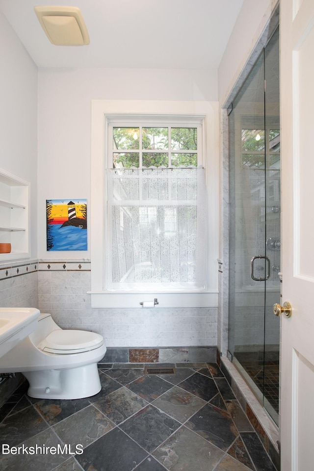 bathroom featuring an enclosed shower, toilet, and tile walls