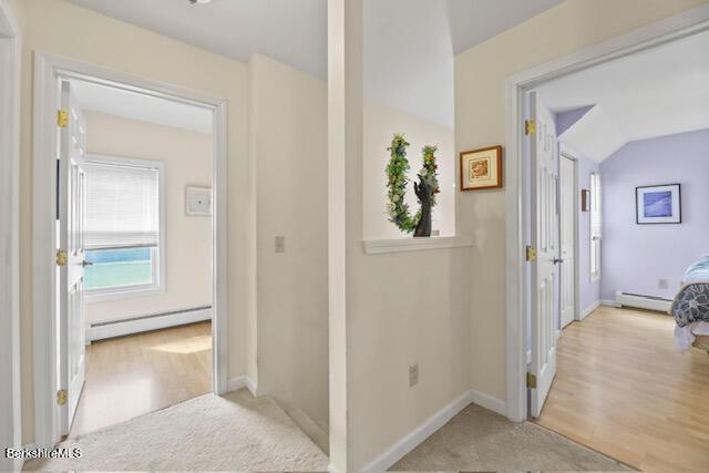 hall featuring carpet floors, a baseboard radiator, baseboards, baseboard heating, and vaulted ceiling