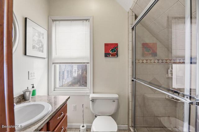 bathroom with vanity, a shower stall, toilet, and baseboards