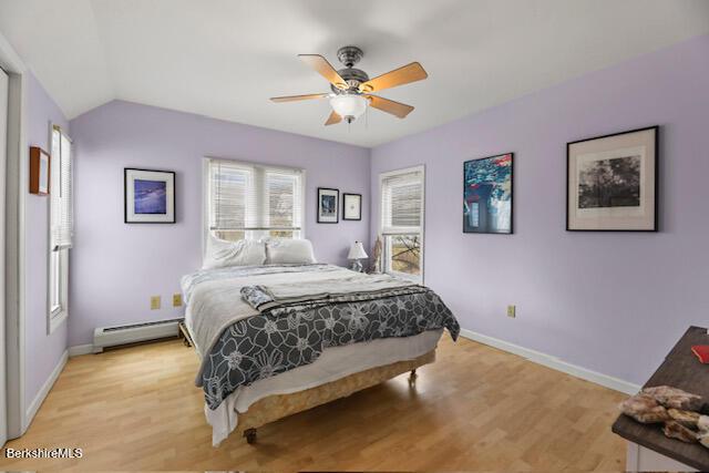 bedroom featuring vaulted ceiling, baseboards, light wood finished floors, and a baseboard radiator